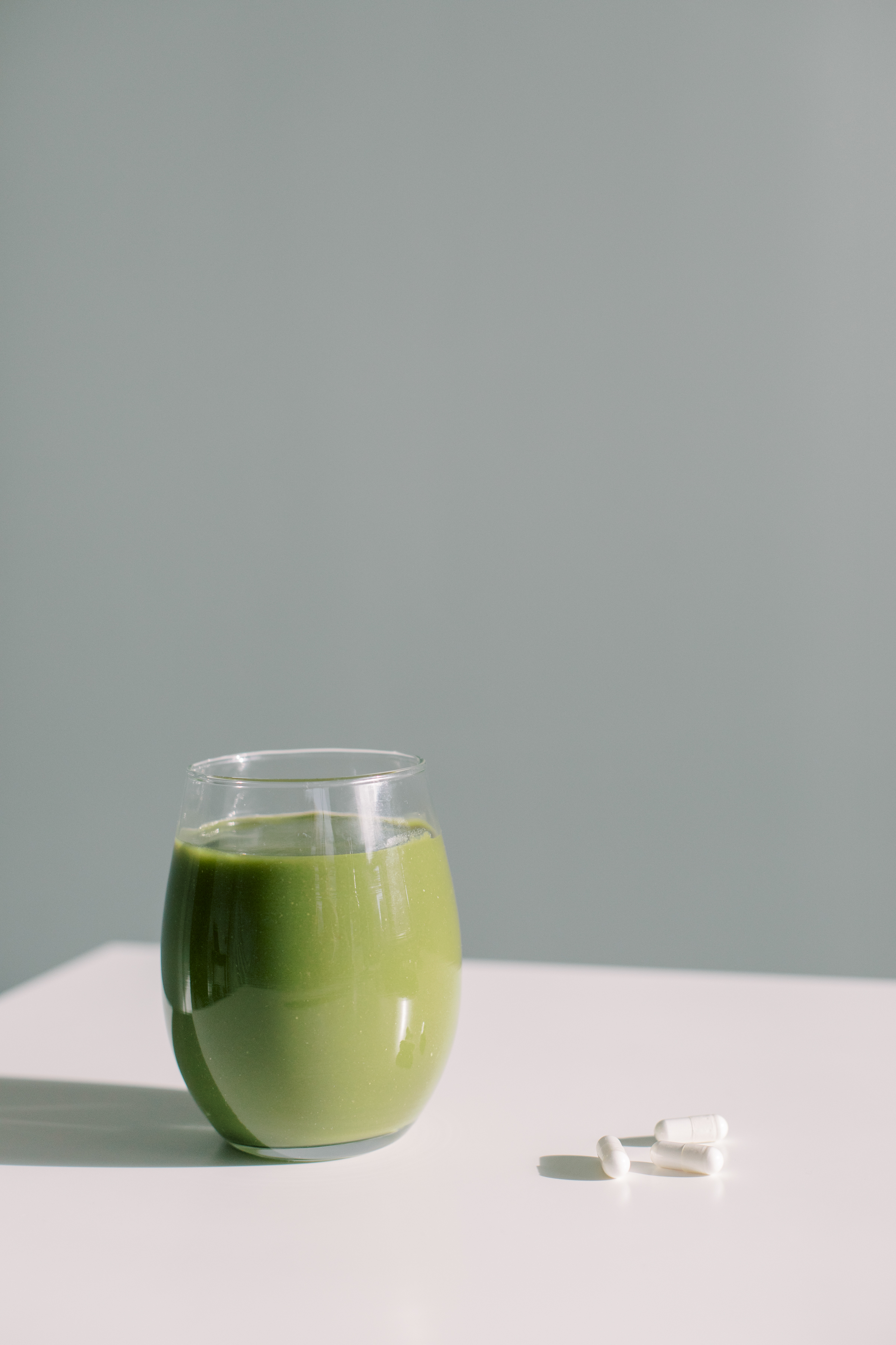 Glass of green smoothie and supplements