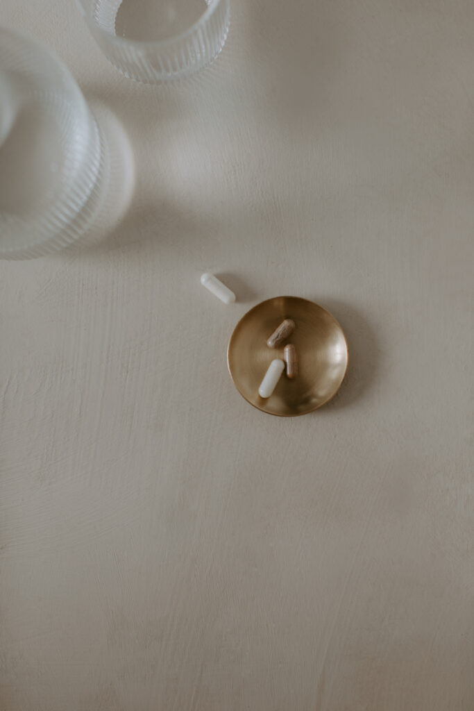 various vitamins and supplements in a brass bowl flat lay